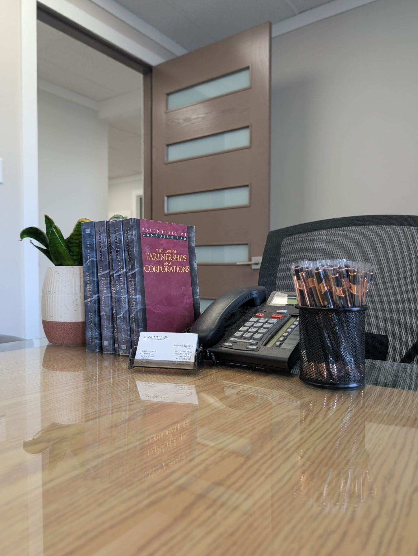 Hashmi Law boardroom table with firm business cards and reference texts